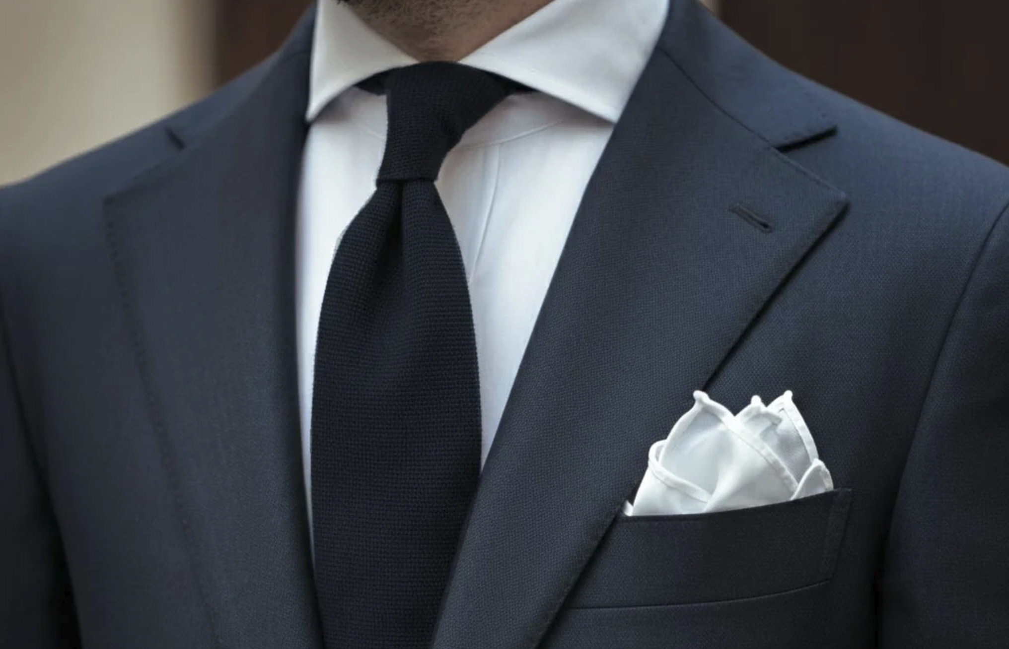 Elegant gentleman wearing a tailored suit with a classic white pocket square as a symbol of timeless style and refinement